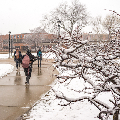 Students walk the paths of the University Commons on a snowy day